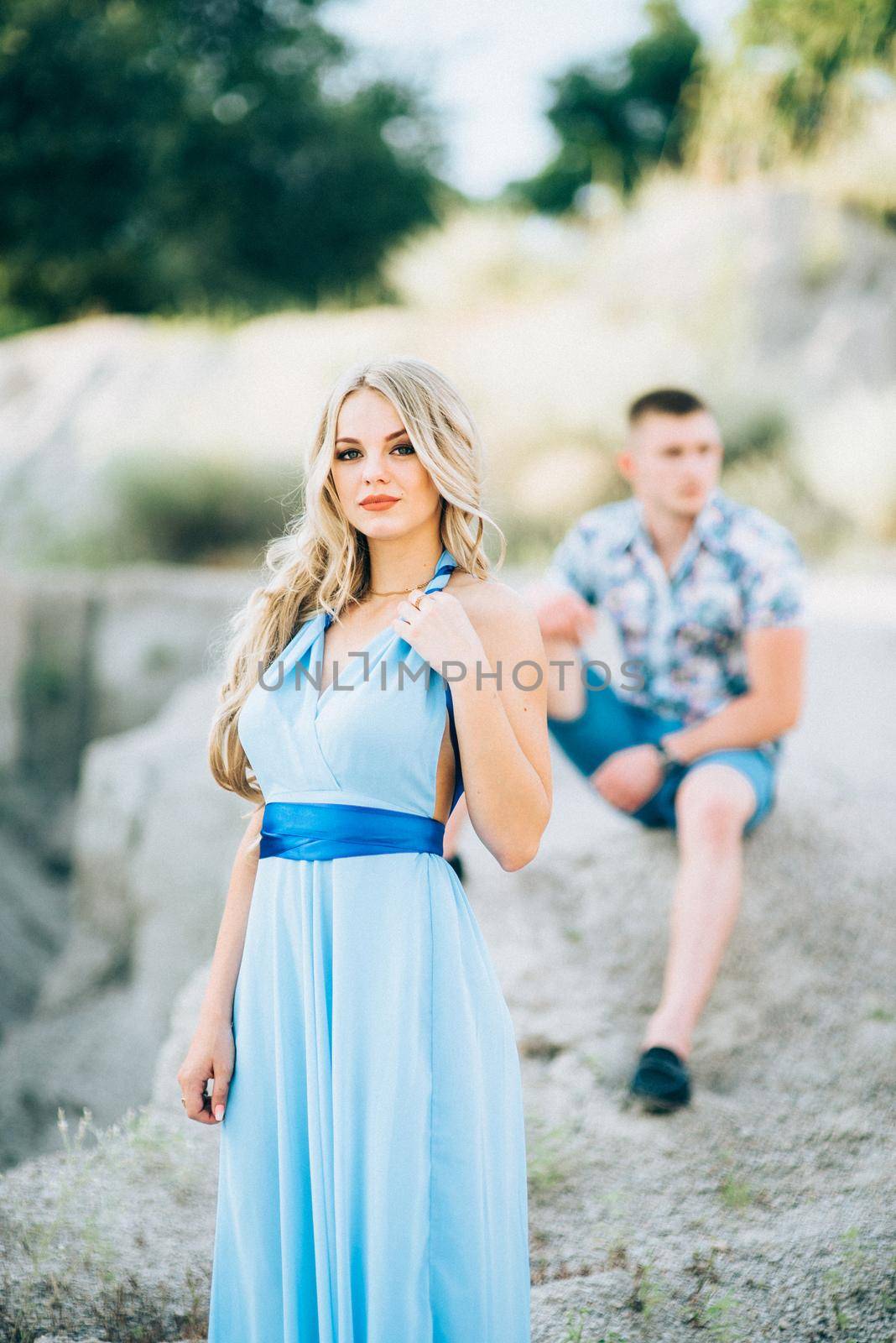 blonde girl in a light blue dress and a guy in a light shorts and short shert in a granite quarry