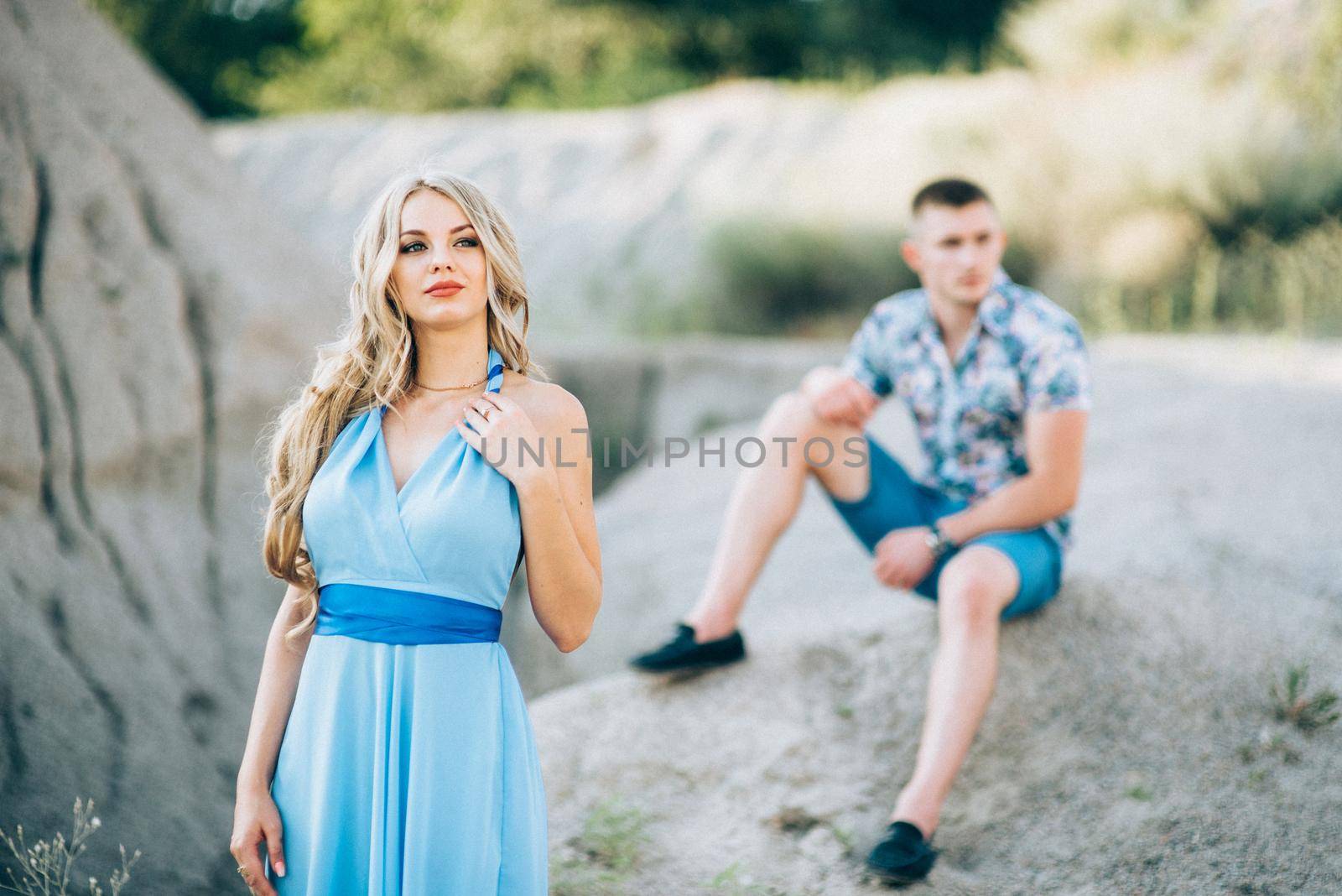 blonde girl in a light blue dress and a guy in a light shorts and short shert in a granite quarry