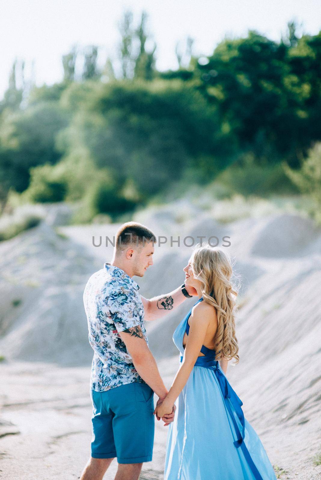 blonde girl in a light blue dress and a guy in a light shorts and short shert in a granite quarry