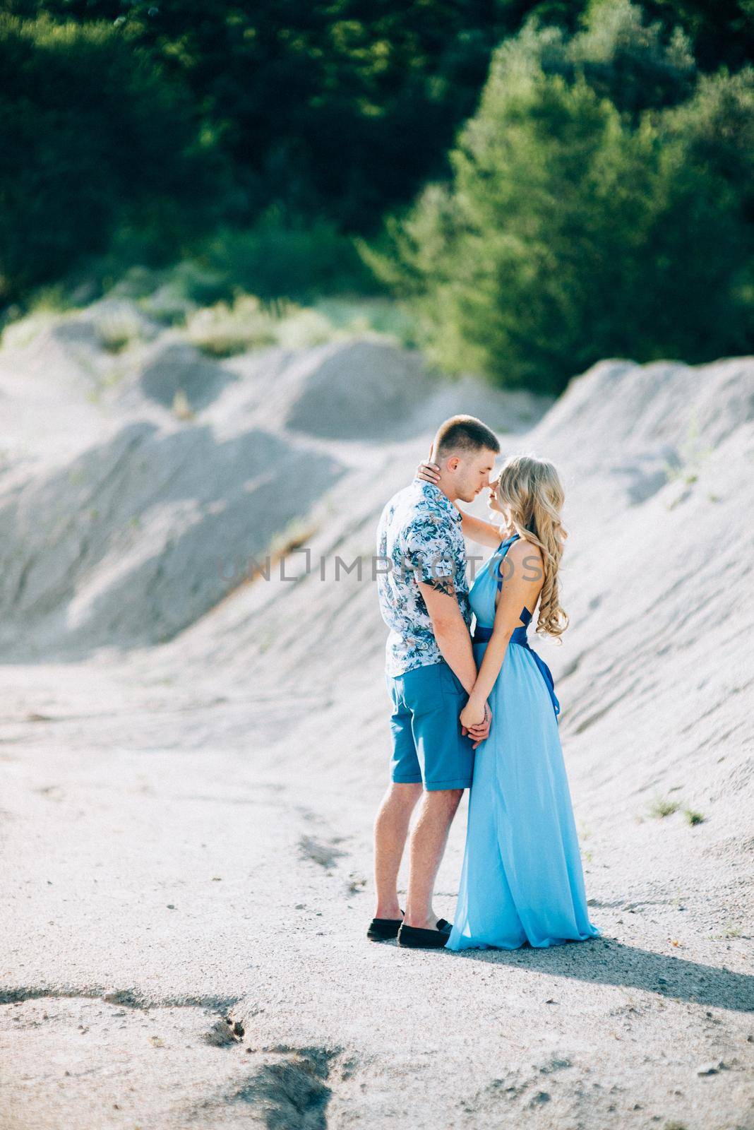 blonde girl in a light blue dress and a guy in a light shorts and short shert in a granite quarry