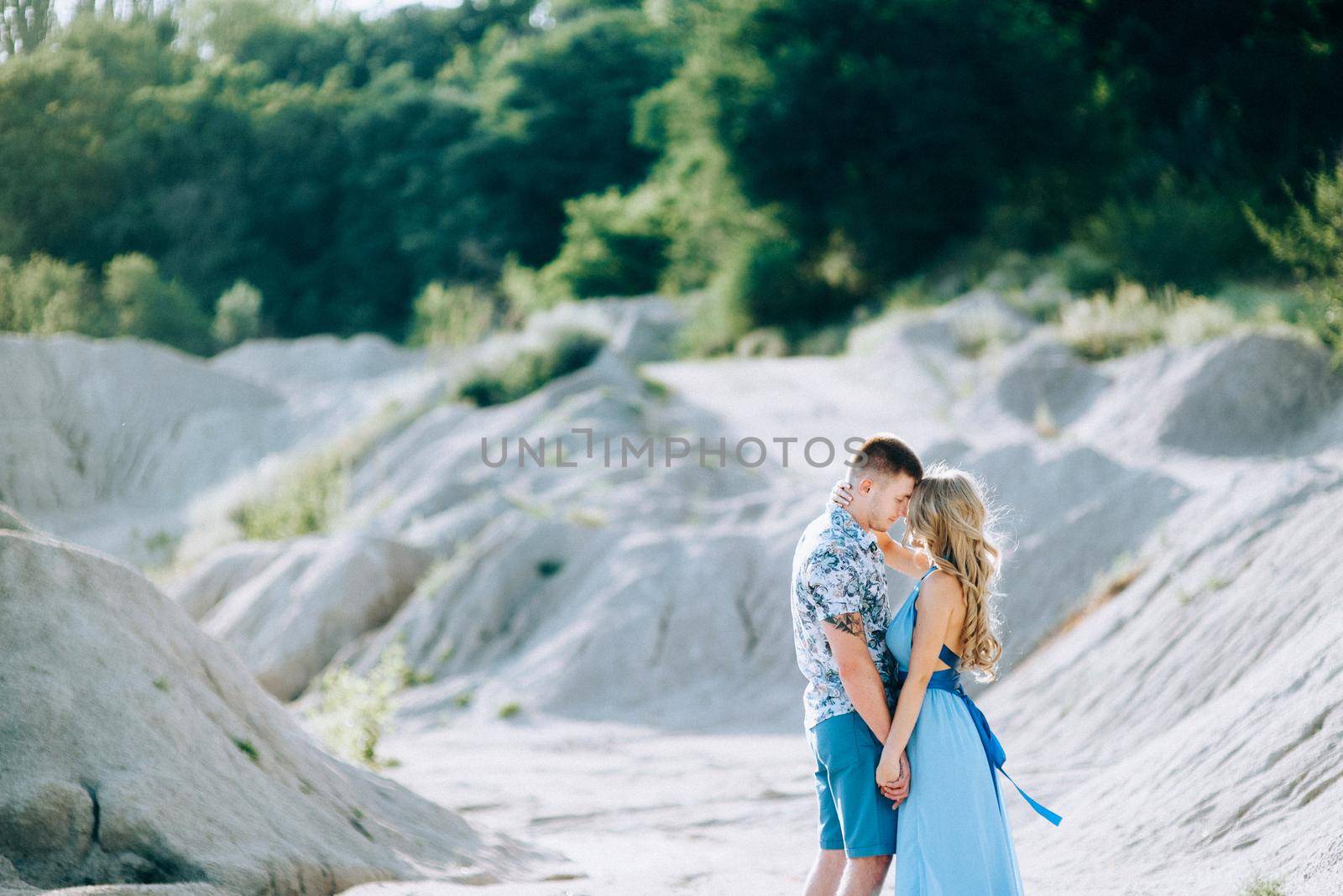 blonde girl in a light blue dress and a guy in a light shorts and short shert in a granite quarry