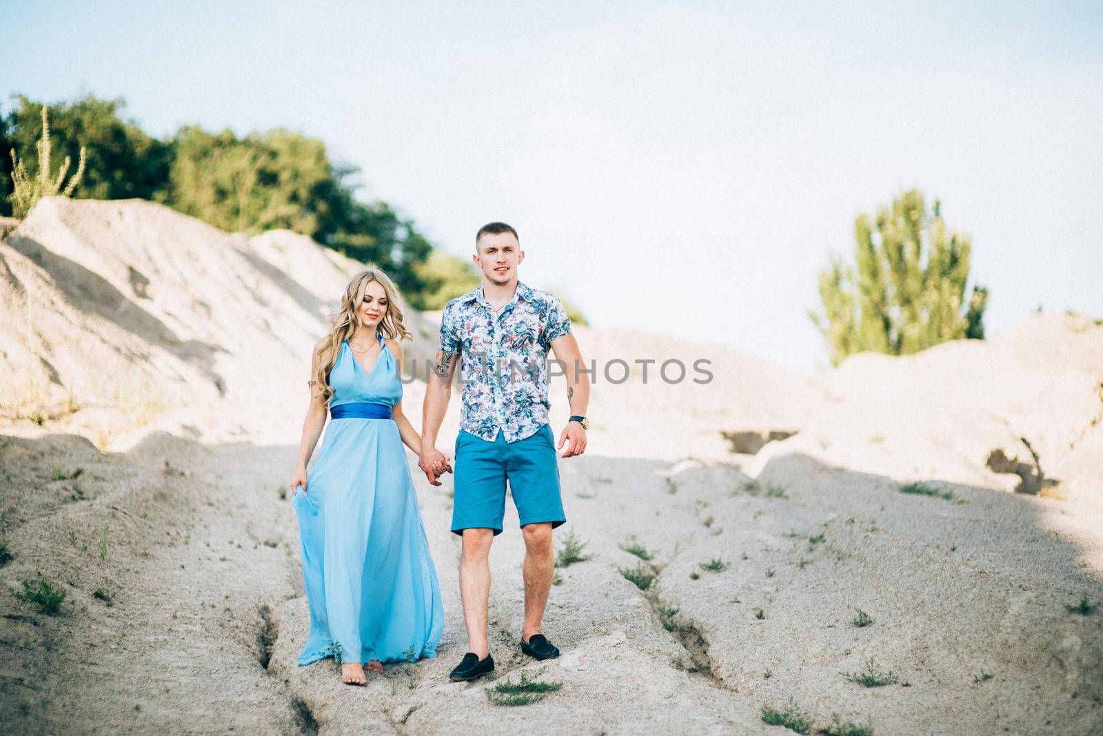 blonde girl in a light blue dress and a guy in a light shorts and short shert in a granite quarry