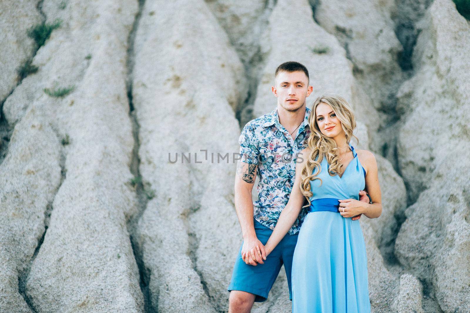 blonde girl in a light blue dress and a guy in a light shorts and short shert in a granite quarry