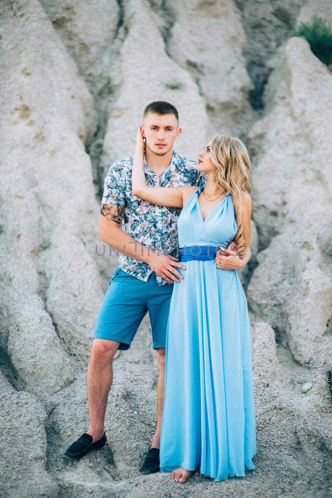 blonde girl in a light blue dress and a guy in a light shorts and short shert in a granite quarry