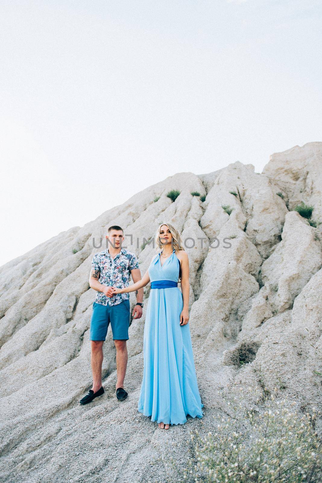 blonde girl in a light blue dress and a guy in a light shorts and short shert in a granite quarry