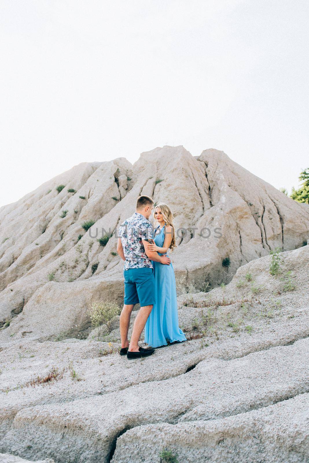 blonde girl in a light blue dress and a guy in a light shorts and short shert in a granite quarry