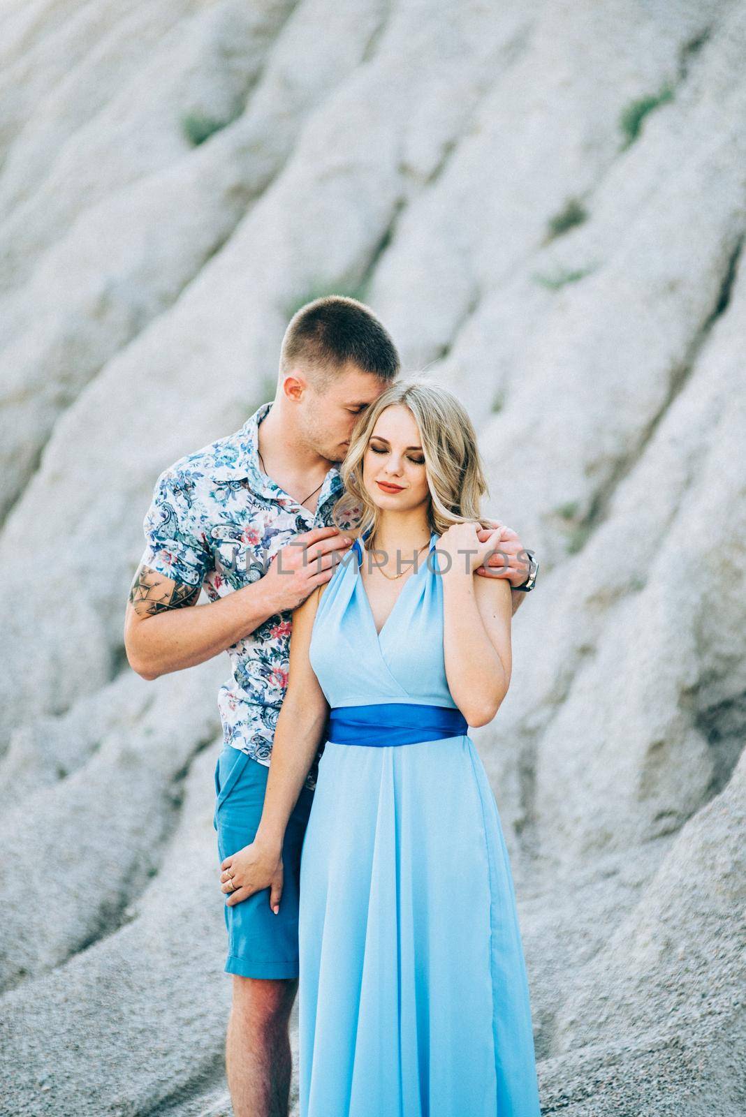 blonde girl in a light blue dress and a guy in a light shorts and short shert in a granite quarry