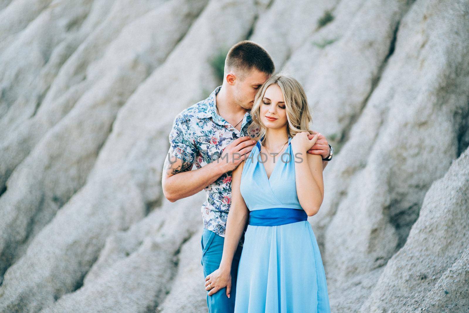 blonde girl in a light blue dress and a guy in a light shorts and short shert in a granite quarry