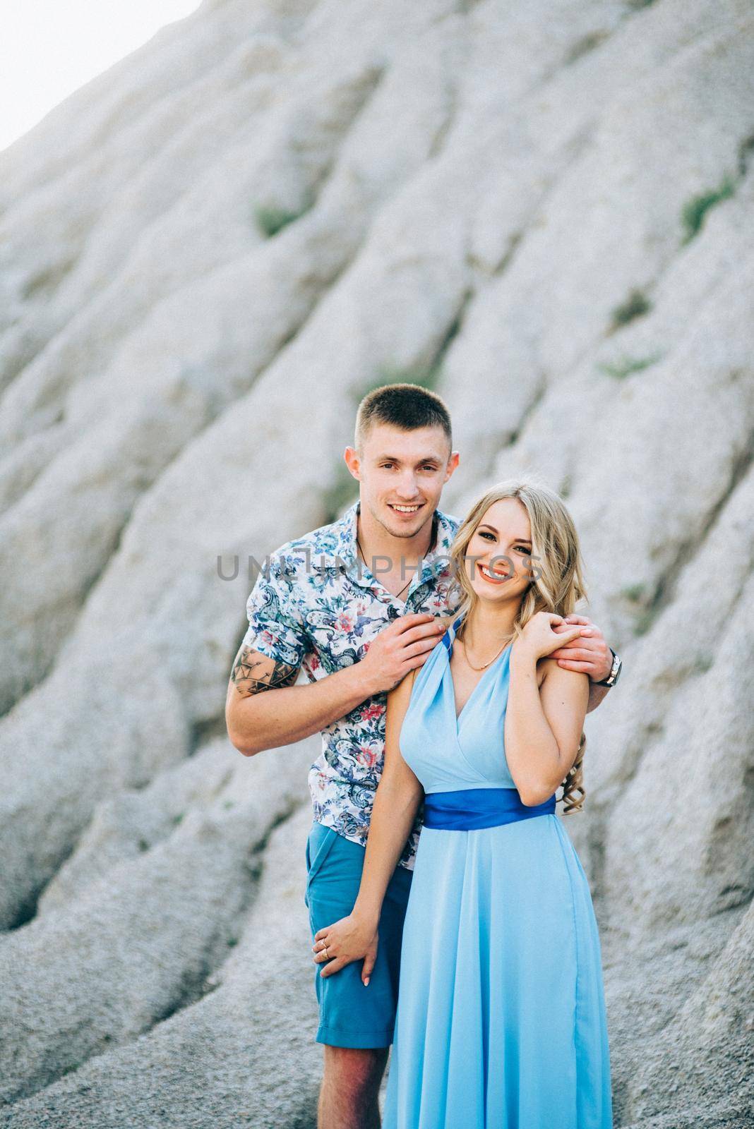 blonde girl in a light blue dress and a guy in a light shorts and short shert in a granite quarry