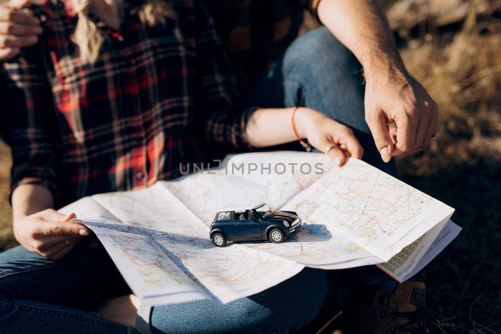 Bald guy with a beard and a blonde girl are looking at the map and looking for a route to travel