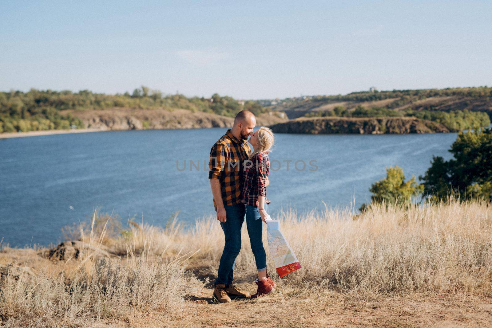 Bald guy with a beard and a blonde girl are looking at the map and looking for by Andreua