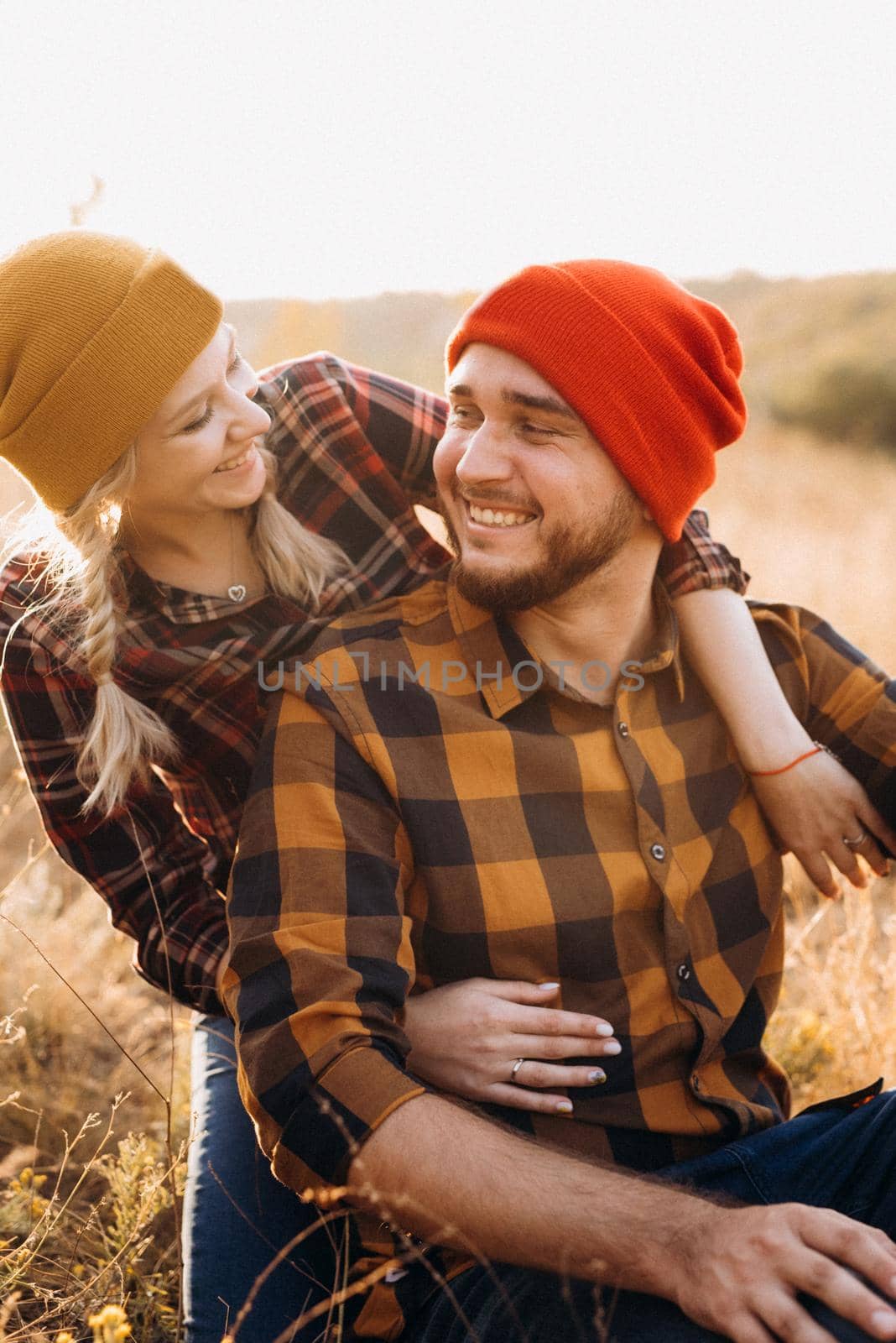 Cheerful guy and girl on a walk in bright knitted hats by Andreua