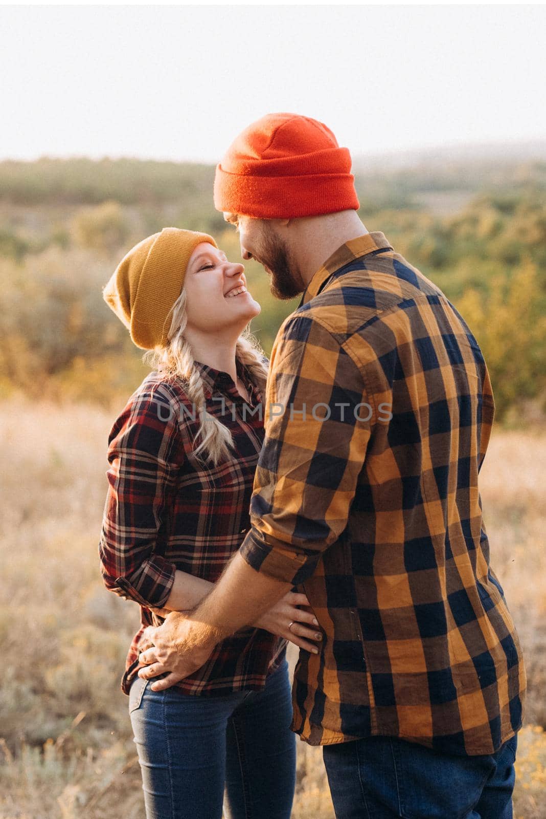 Cheerful guy and girl on a walk in bright knitted hats by Andreua