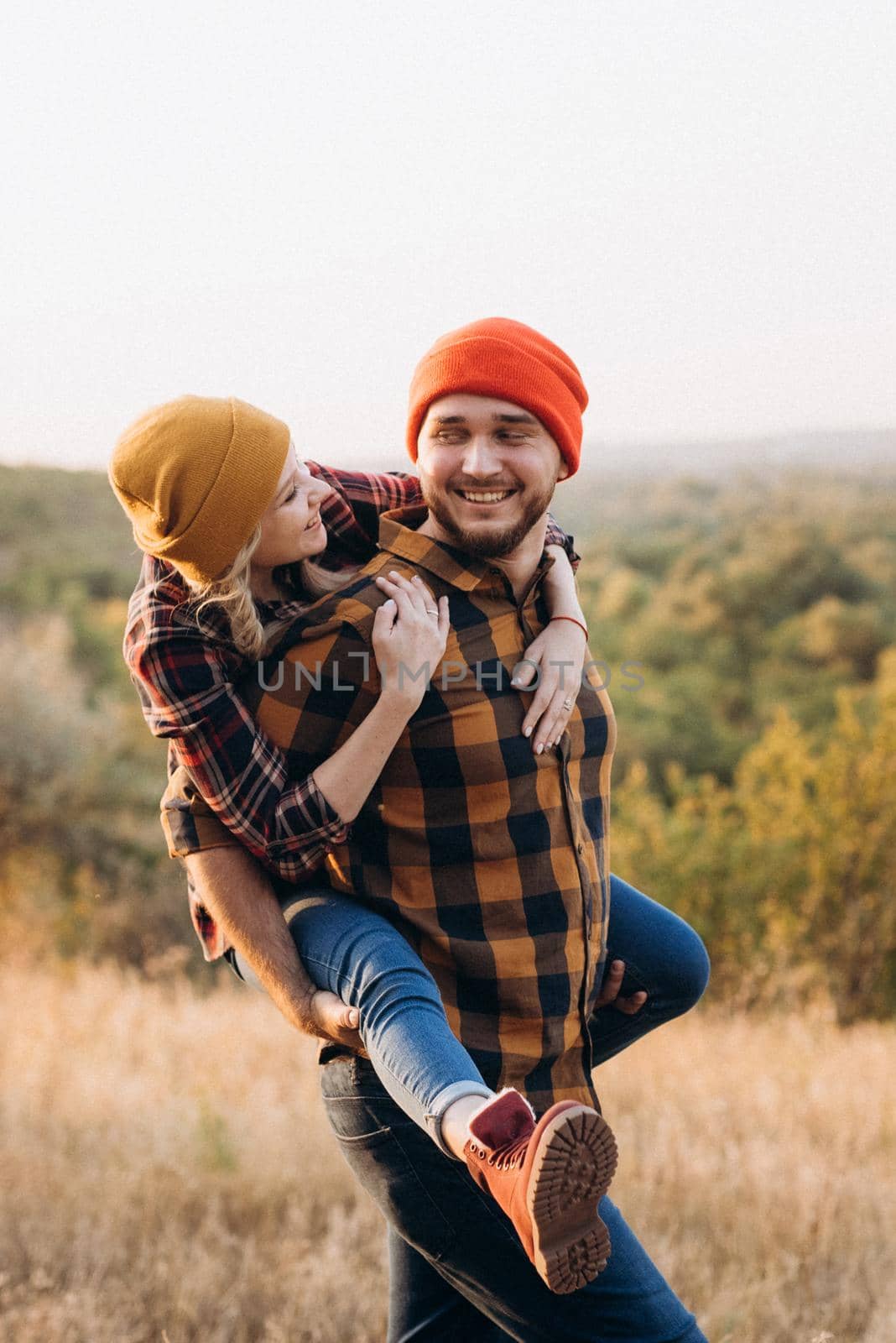 Cheerful guy and girl on a walk in bright knitted hats and plaid shirts