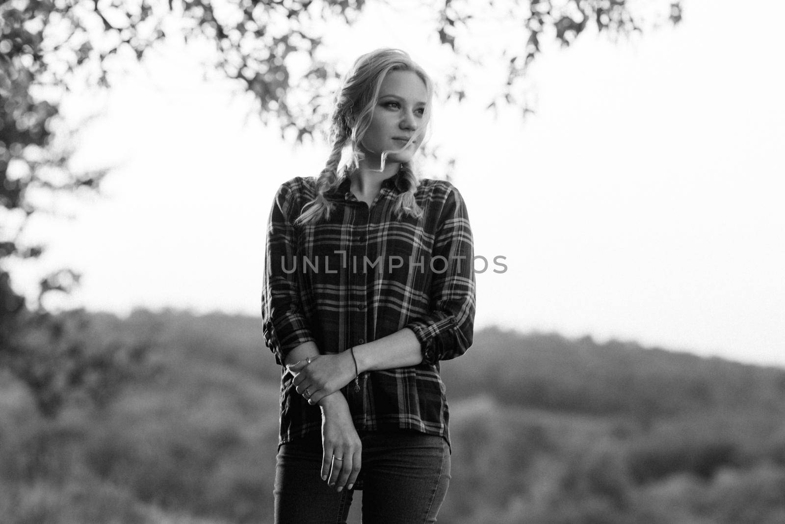 blonde with pigtails in a shirt, jeans, red shoes smiling at sunset