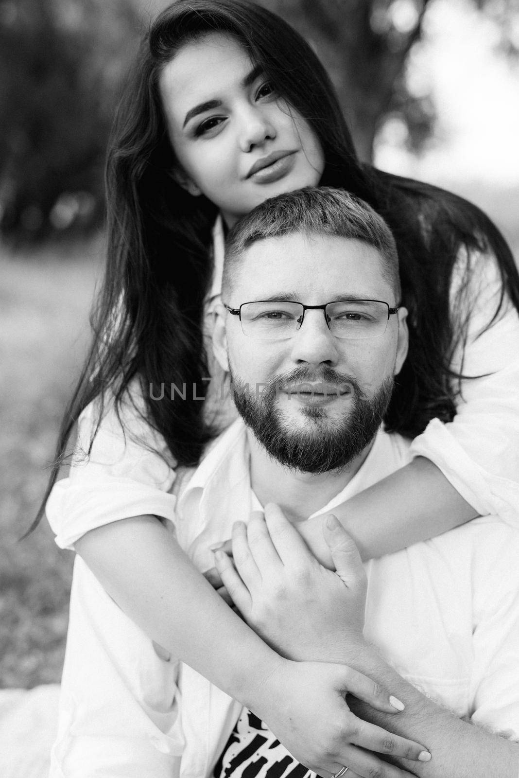 young couple in love a guy with a beard and a girl with dark hair in light clothes in the green forest