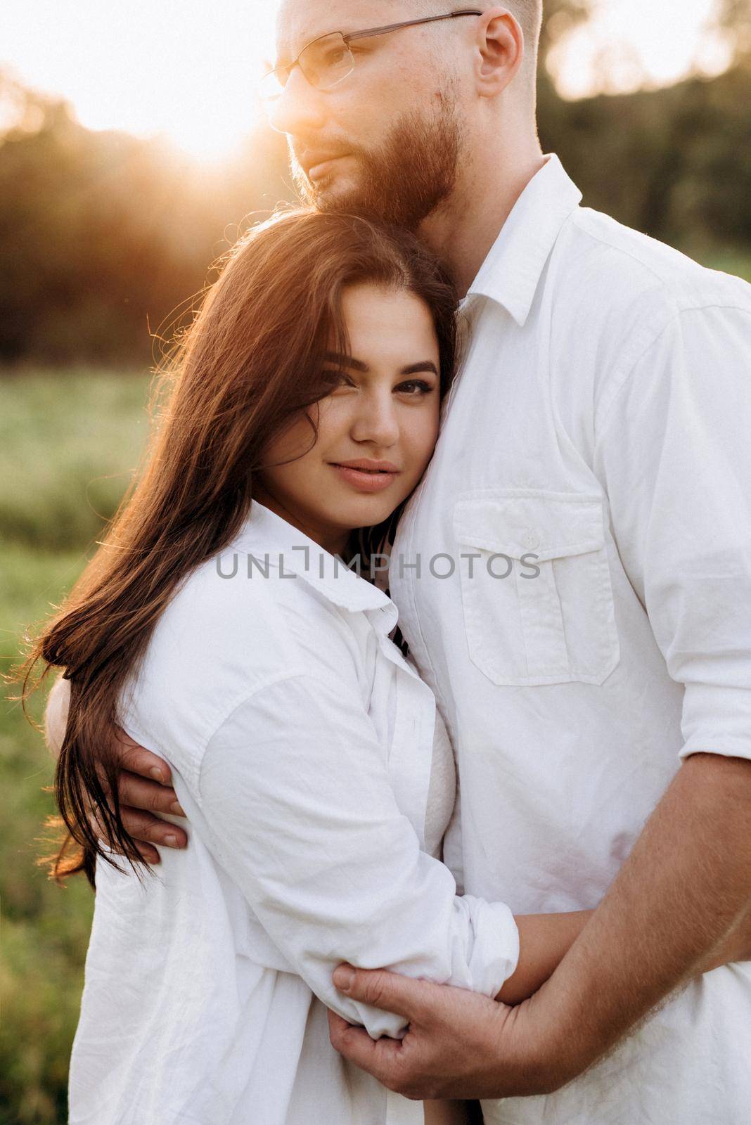 young couple in love a guy with a beard and a girl with dark hair in light clothes in the green forest