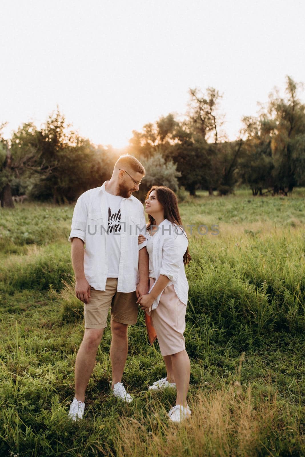 young couple in love a guy with a beard and a girl with dark hair in light clothes in the green forest