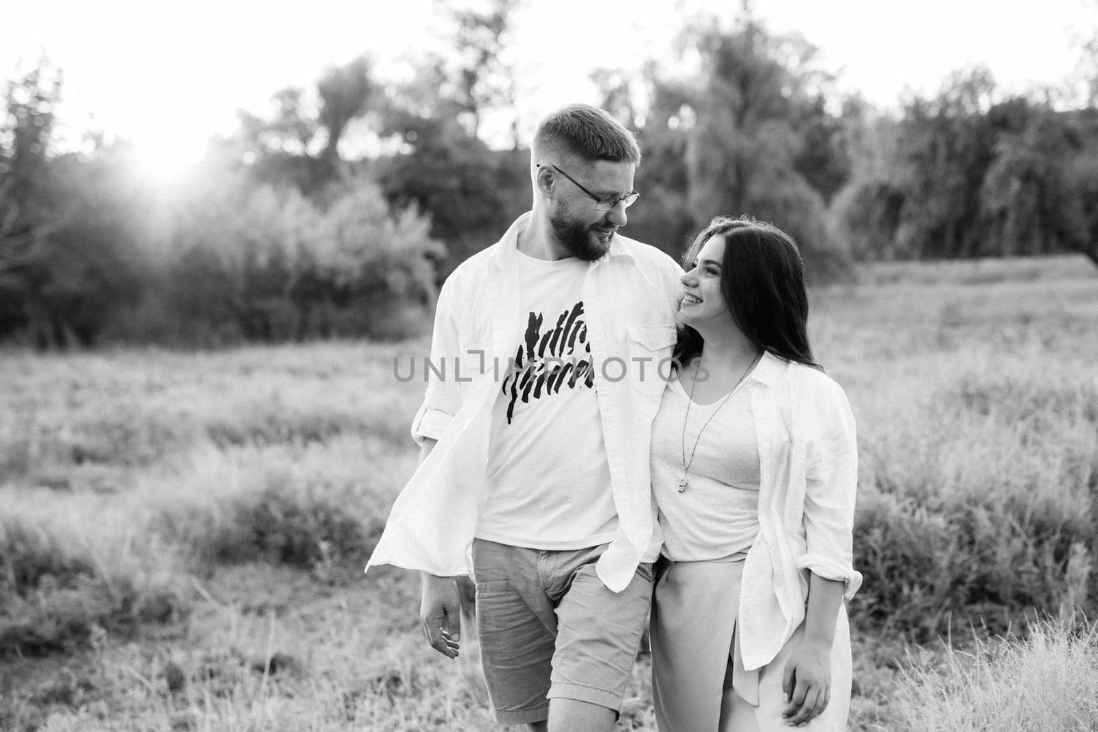 young couple in love a guy with a beard and a girl with dark hair in light clothes in the green forest