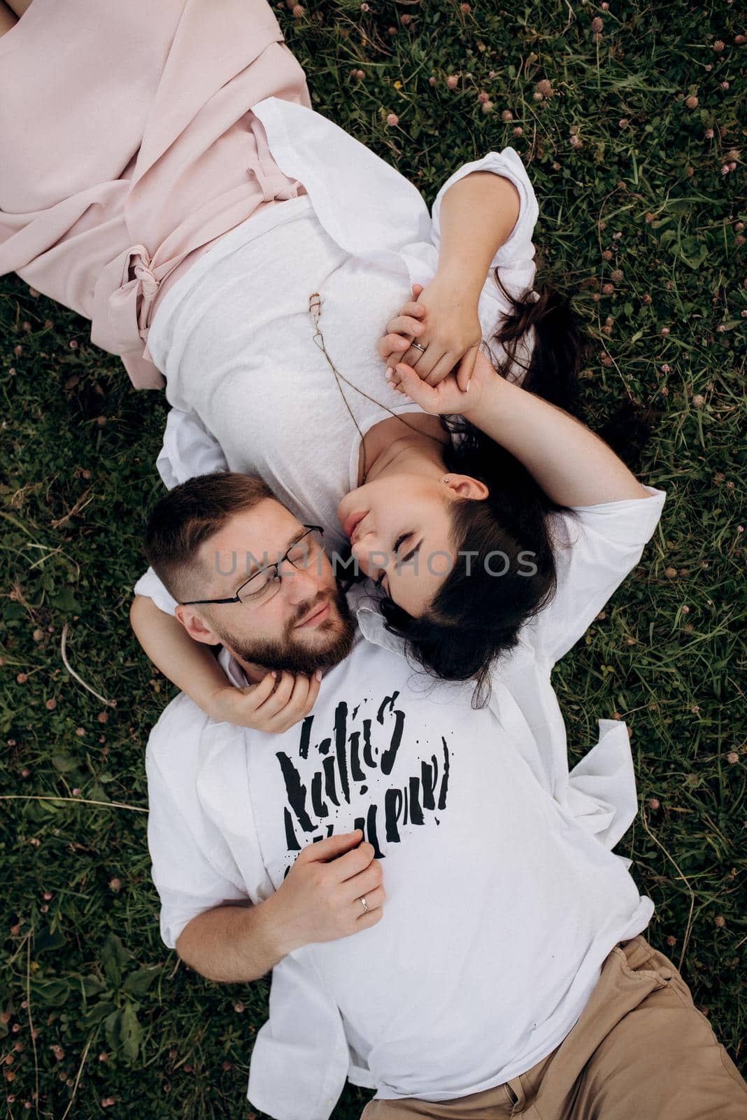 young couple in love a guy with a beard and a girl with dark hair in light clothes in the green forest