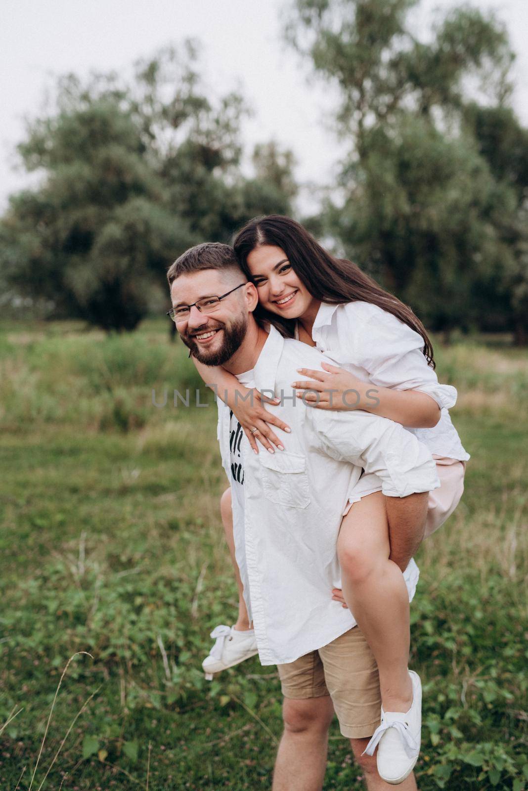 young couple in love a guy with a beard and a girl with dark hair in light clothes in the green forest