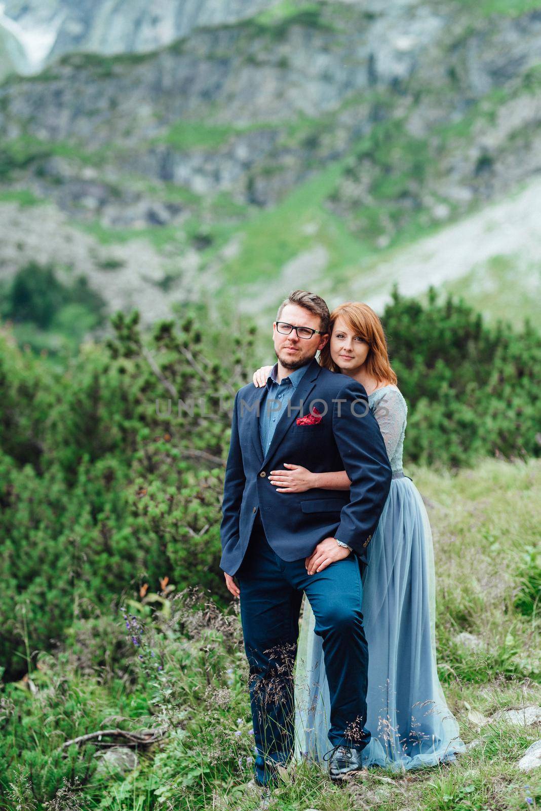 young couple on a walk near the lake surrounded by the mountains by Andreua