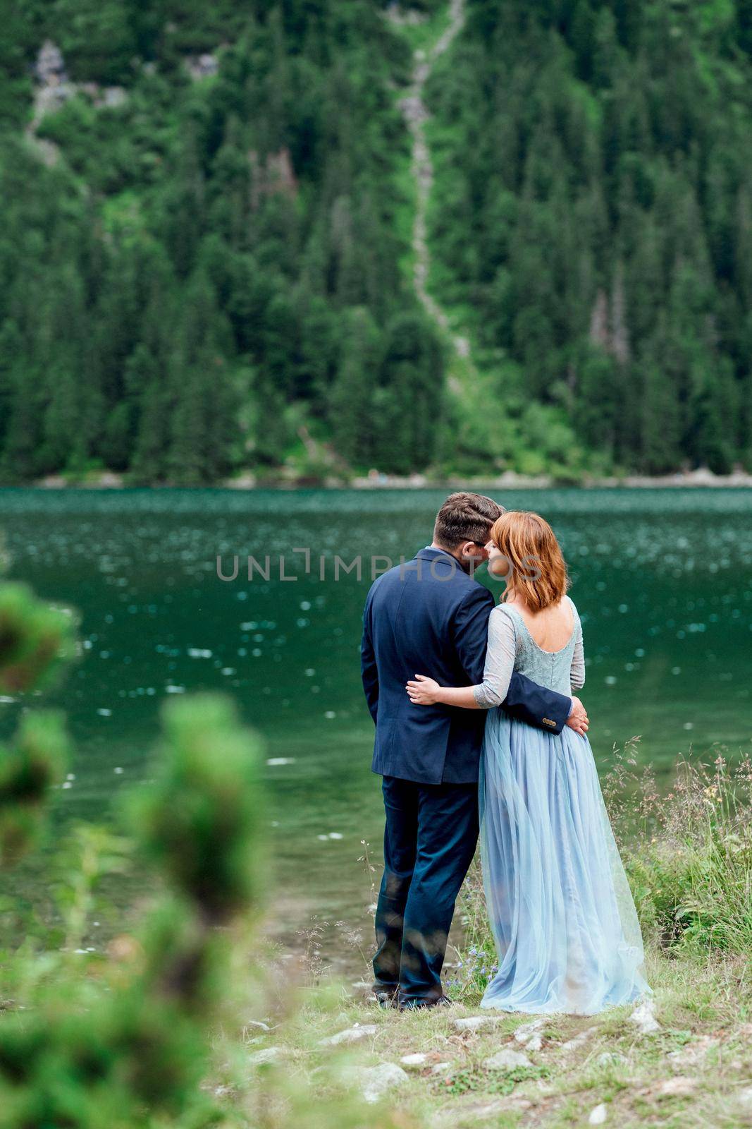 young couple on a walk near the lake surrounded by the mountains by Andreua
