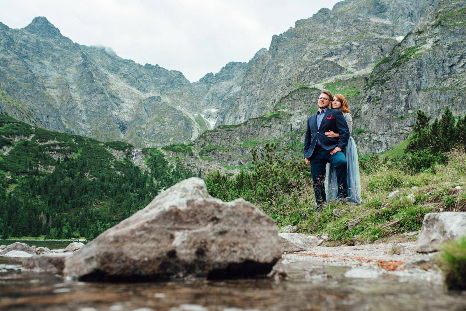 young couple on a walk near the lake surrounded by the mountains by Andreua