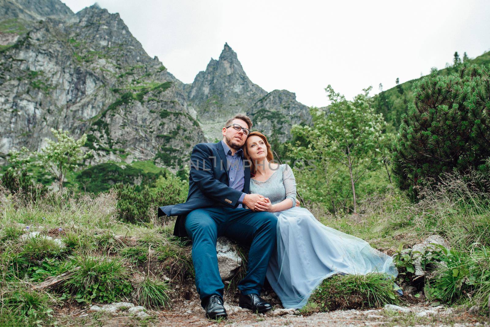 young couple on a walk near the lake surrounded by the mountains by Andreua