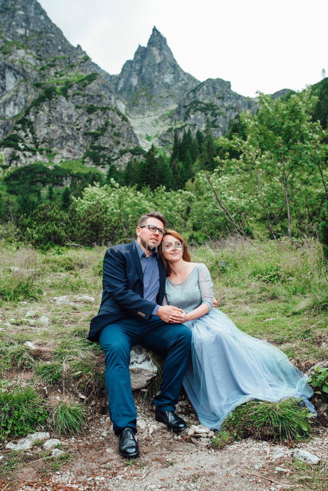 young couple on a walk near the lake surrounded by the mountains by Andreua