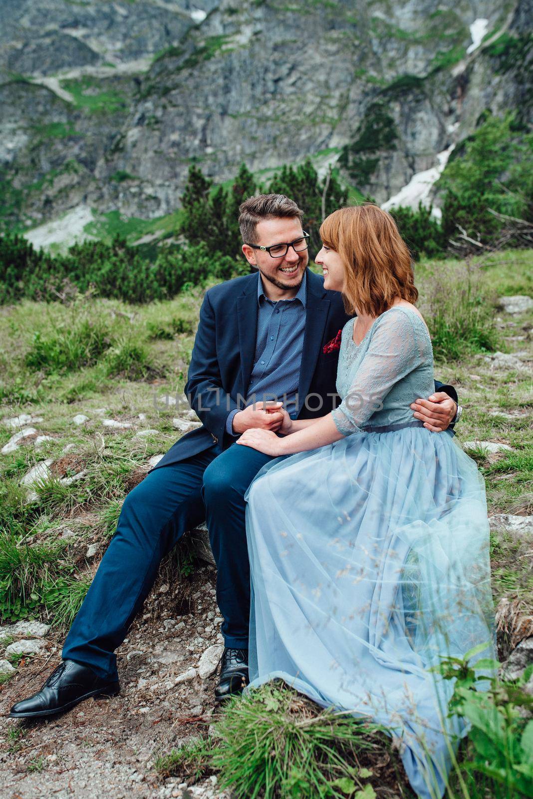 young couple on a walk near the lake surrounded by the mountains by Andreua