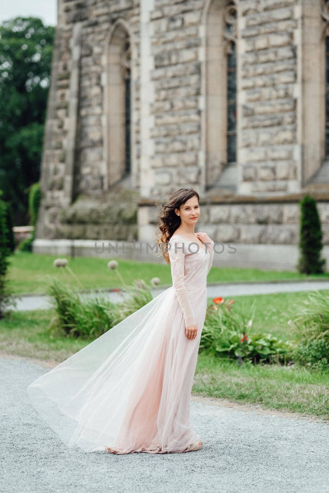 A girl in a light pink dress against the background of a medieval Polish stone castle