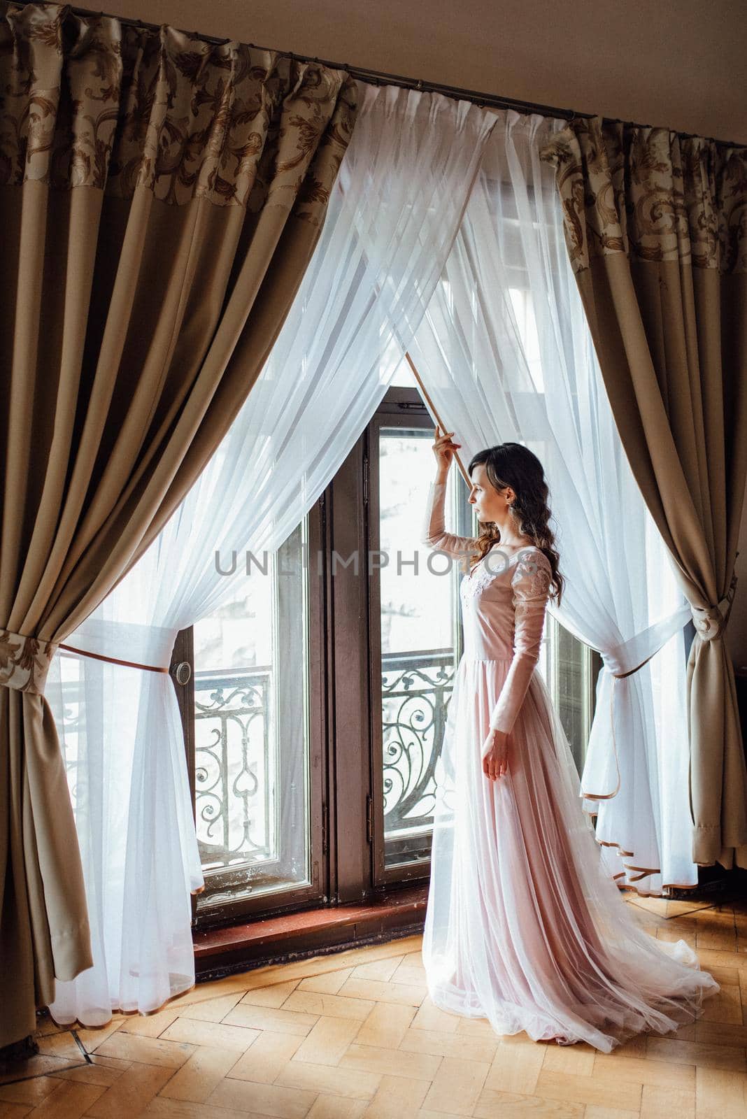 A girl in a light pink dress against the background of a medieval Polish stone castle