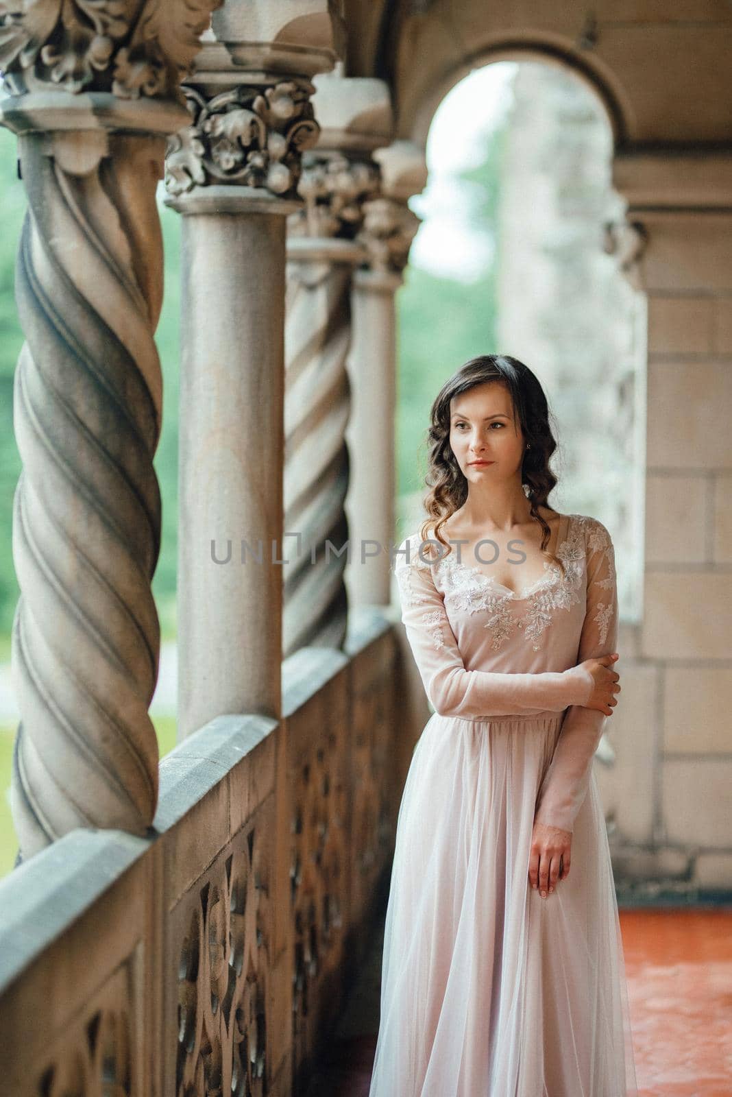 A girl in a light pink dress against the background of a medieval Polish stone castle