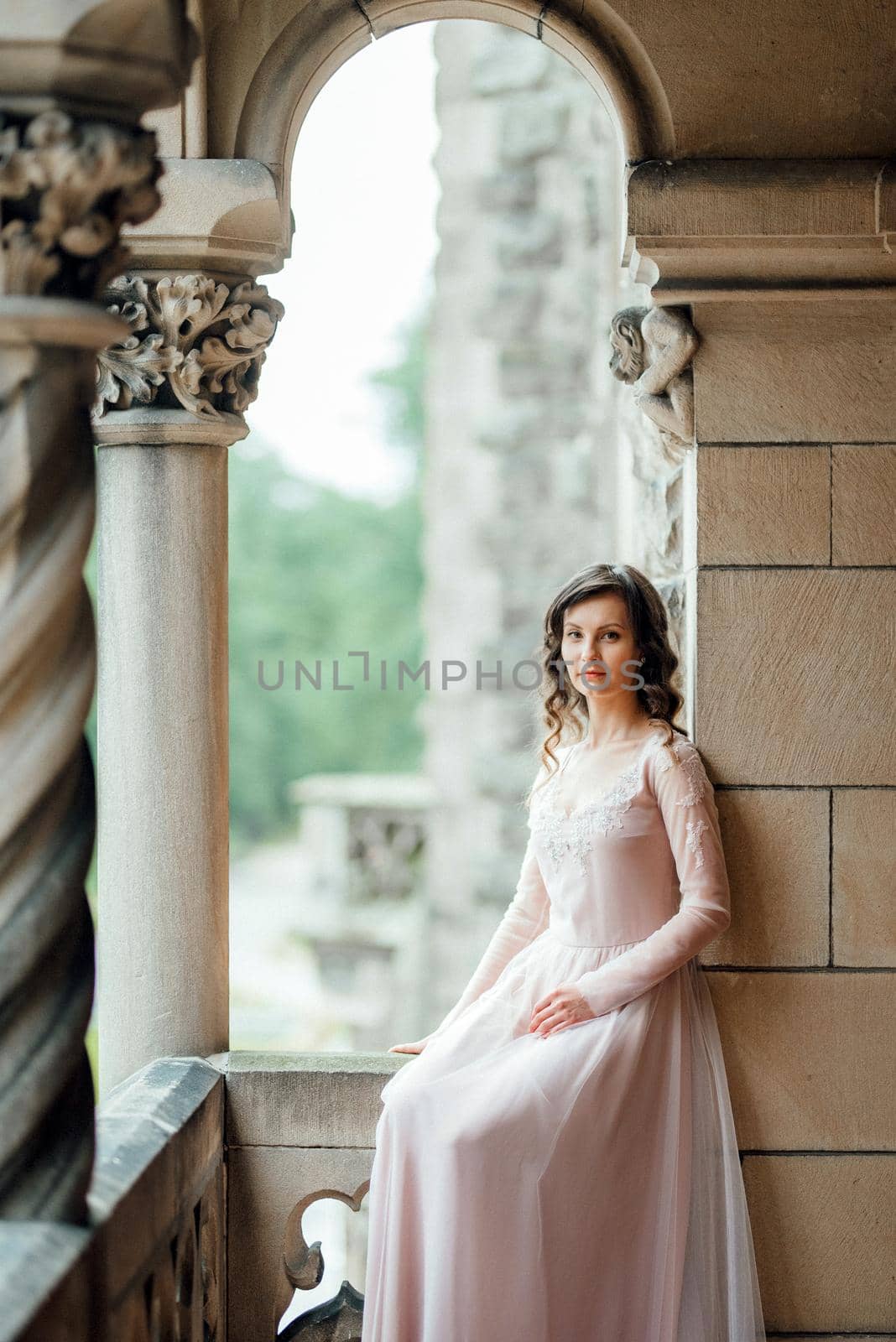 A girl in a light pink dress against the background of a medieval Polish stone castle