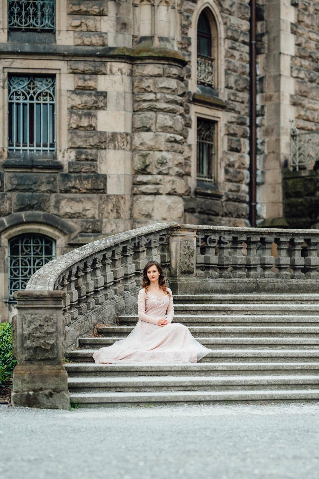 A girl in a light pink dress against the background of a medieval Polish stone castle