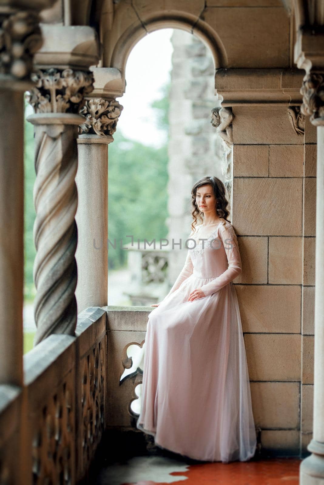 A girl in a light pink dress against the background of a medieval Polish stone castle