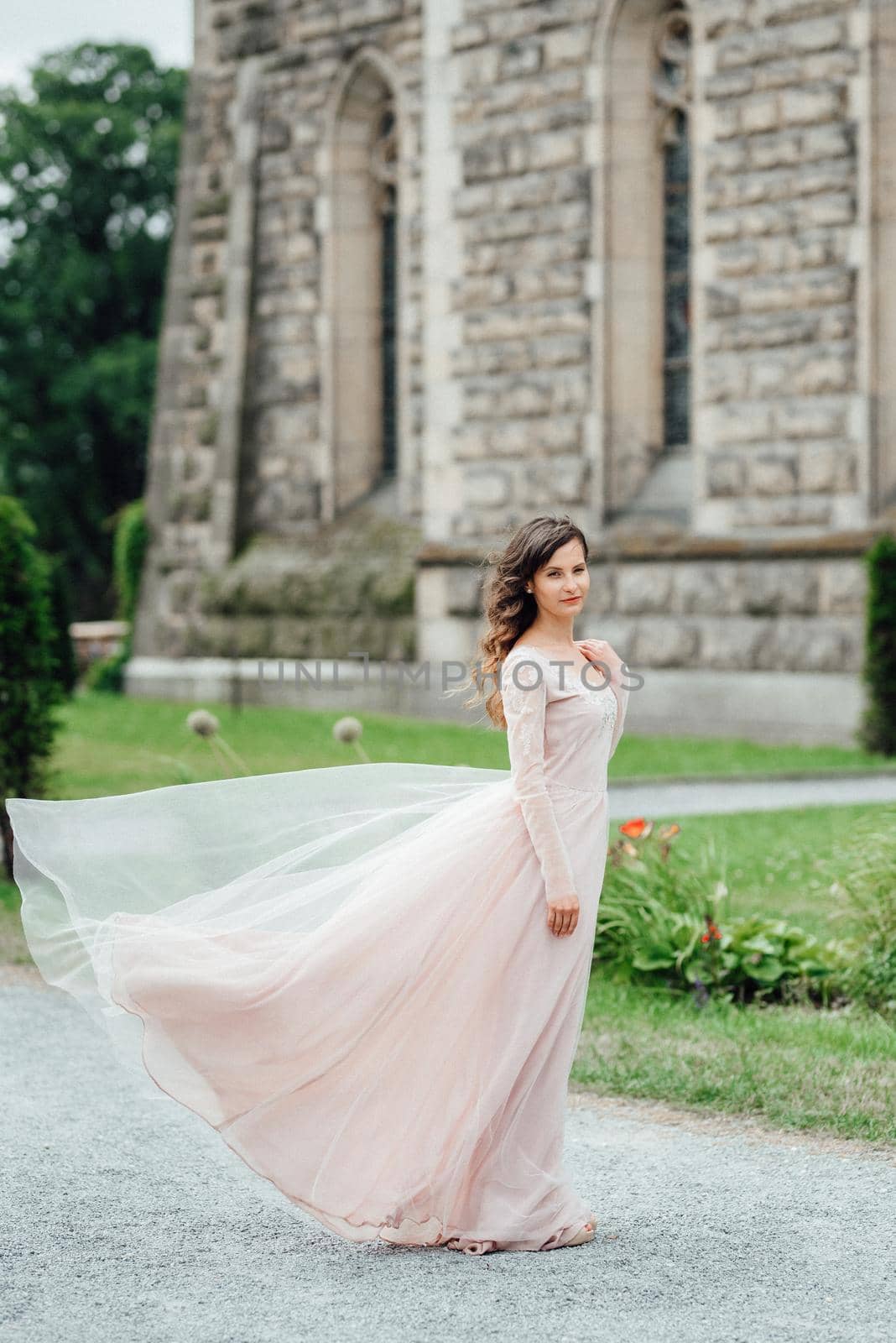 A girl in a light pink dress against the background of a medieval Polish stone castle