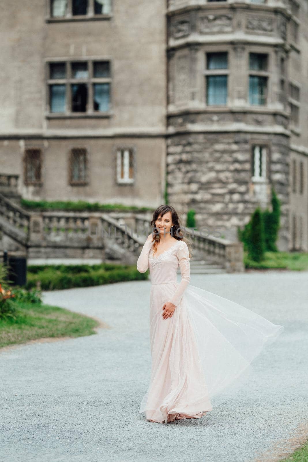 A girl in a light pink dress against the background of a medieval Polish stone castle