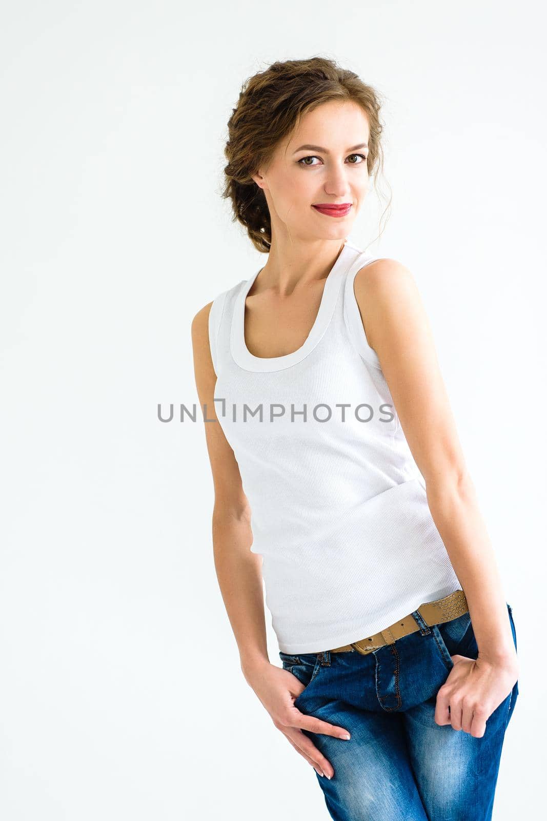 cheerful girl in a white t-shirt and dark blue jeans in the studio on a white background by Andreua