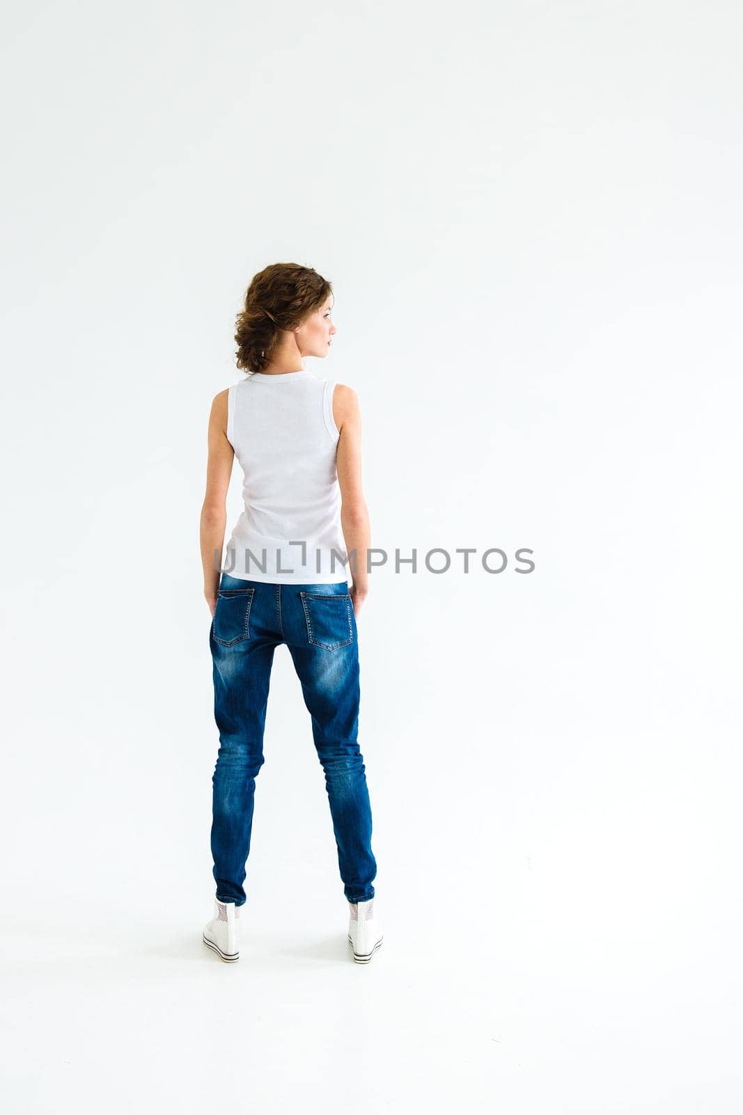 cheerful girl in a white t-shirt and dark blue jeans in the studio on a white background by Andreua