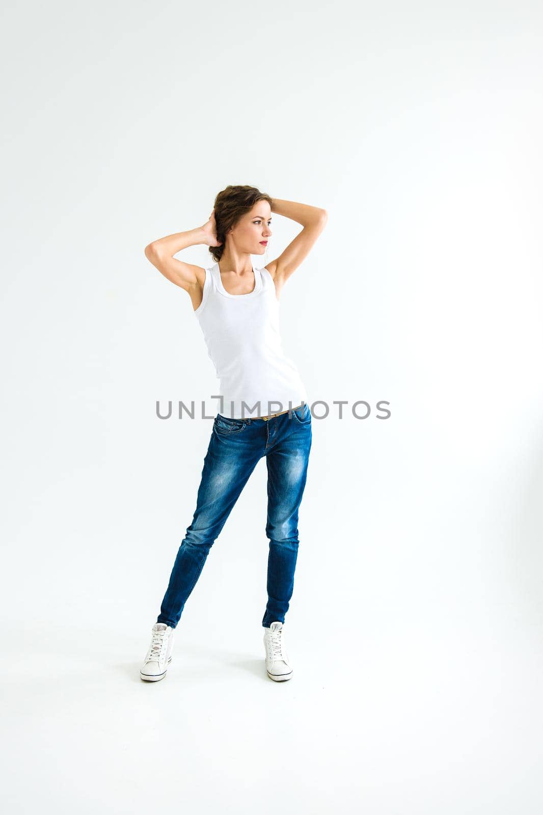 cheerful girl in a white t-shirt and dark blue jeans in the studio on a white background stands, sits, runs