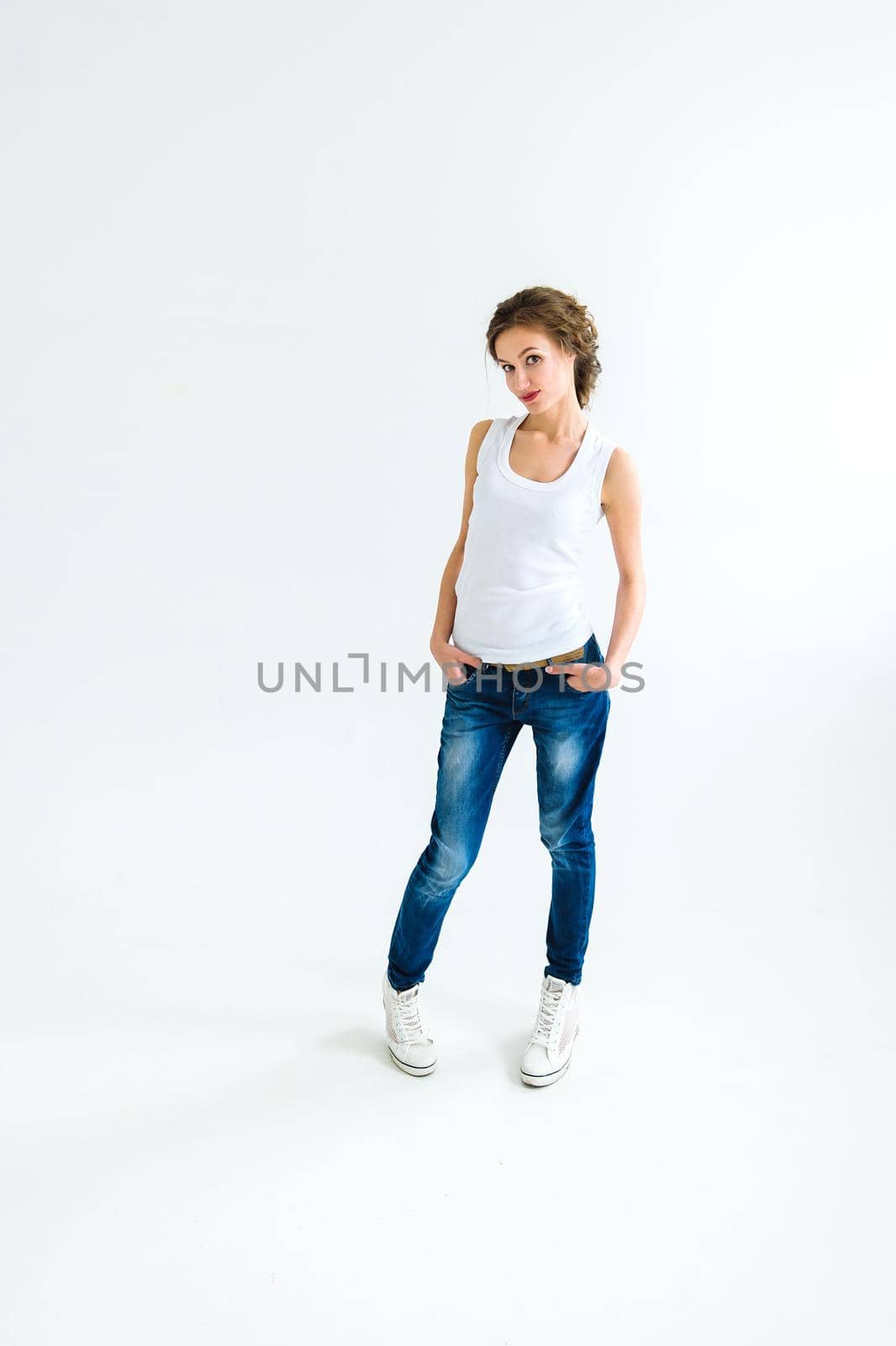 cheerful girl in a white t-shirt and dark blue jeans in the studio on a white background stands, sits, runs