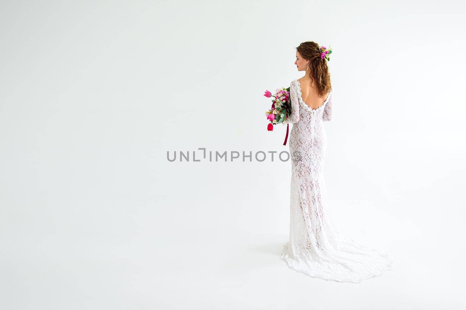 joyful girl bride in a white knitted dress posing with a bouquet of flowers in the studio on a white background