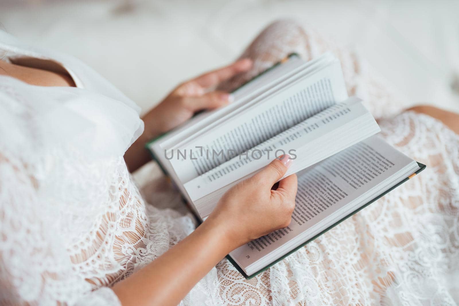 girl with black hair reads a book in Russian sitting on a light leather sofa