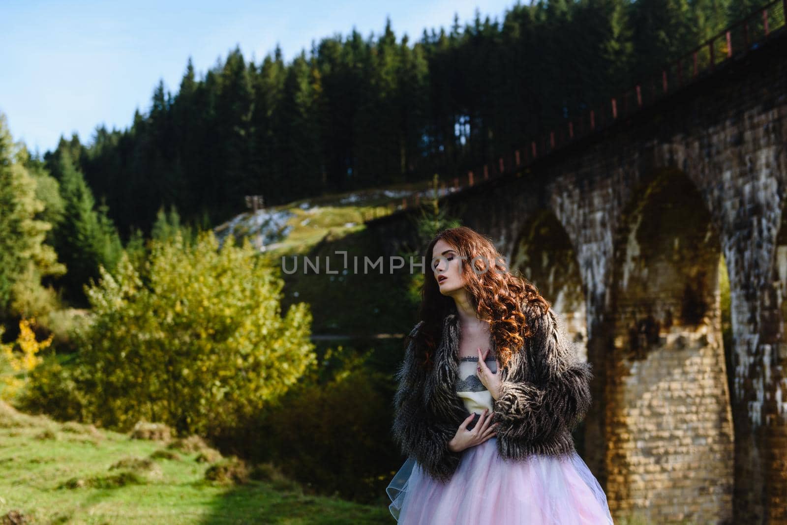 the bride walks under a bridge in a fur Cape in the Carpathians