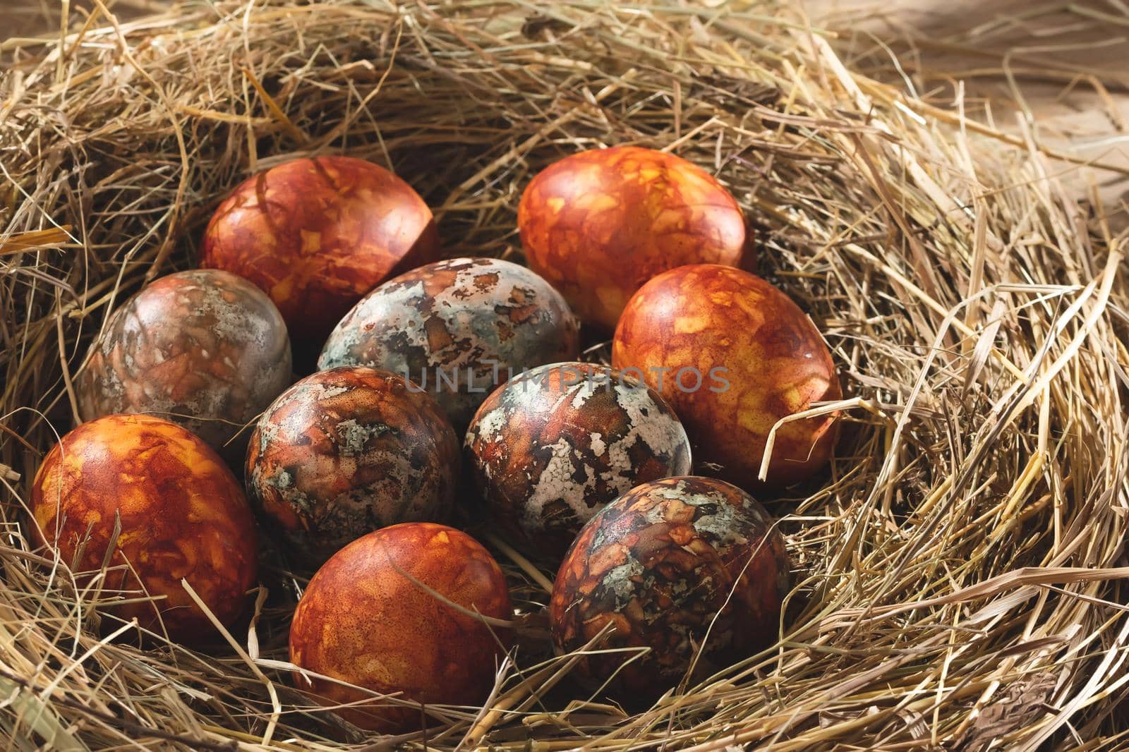 Easter composition - orange marble Easter eggs painted with natural dyes in a nest of hay by galsand