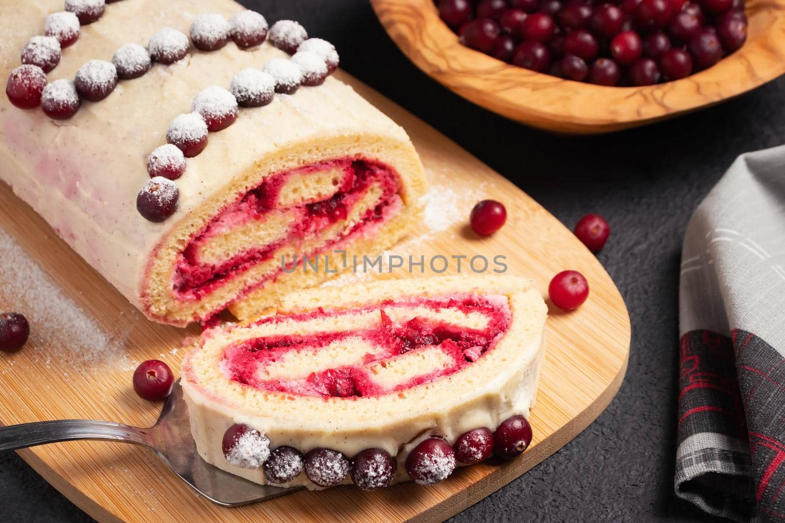 Homemade biscuit sweet roll with cranberries and cream on a black table by galsand