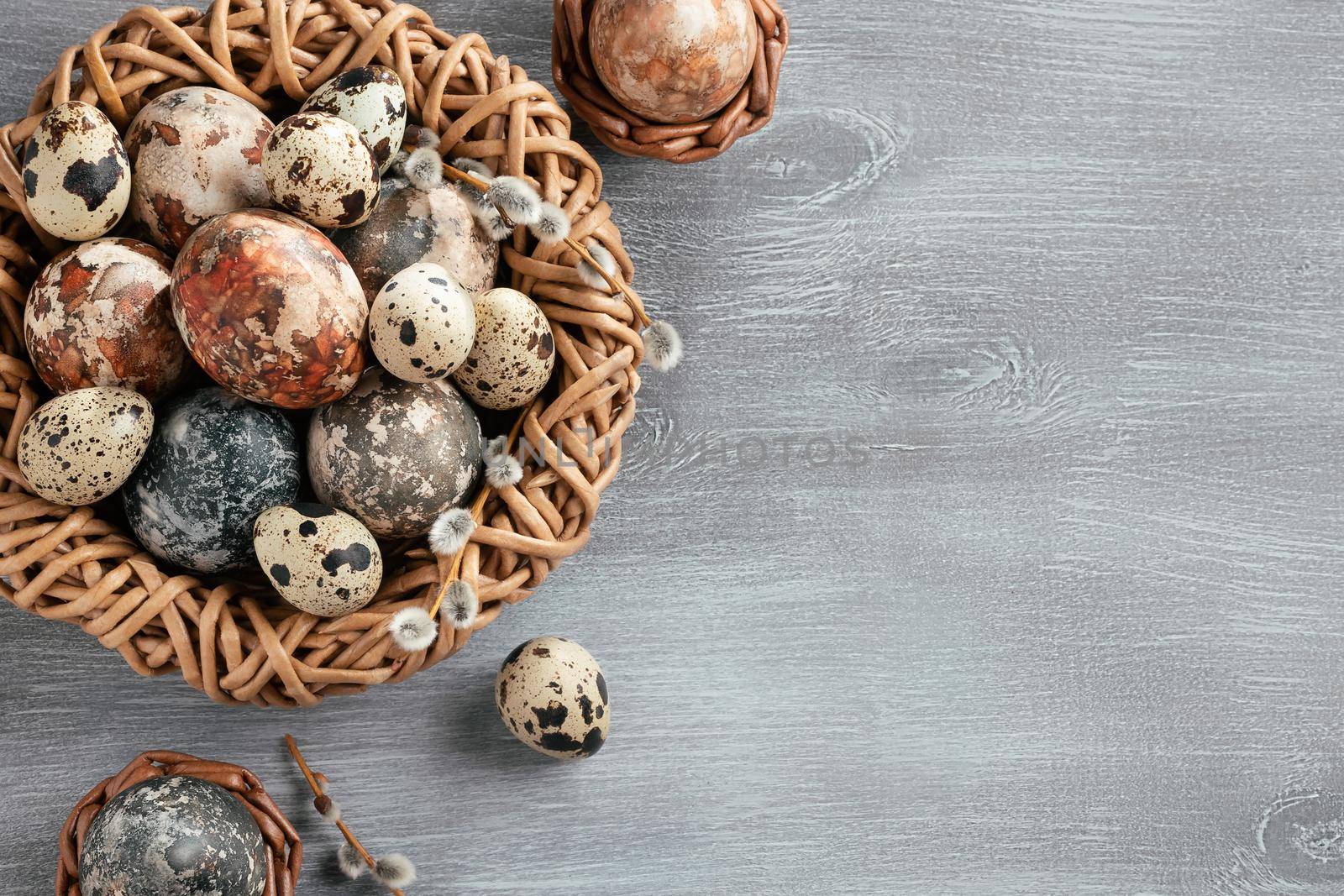 Easter composition - several marble eggs painted with natural dyes in a wicker nest and baskets, top veiw by galsand