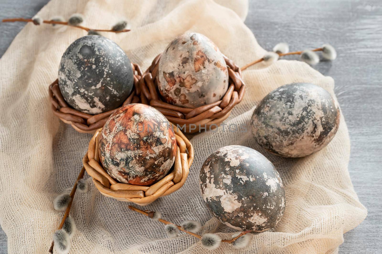 Easter composition - several marble eggs painted with natural dyes in a wicker baskets.
